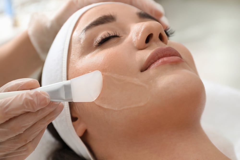 Woman receiving a facial peel treatment to improve skin texture and tone.